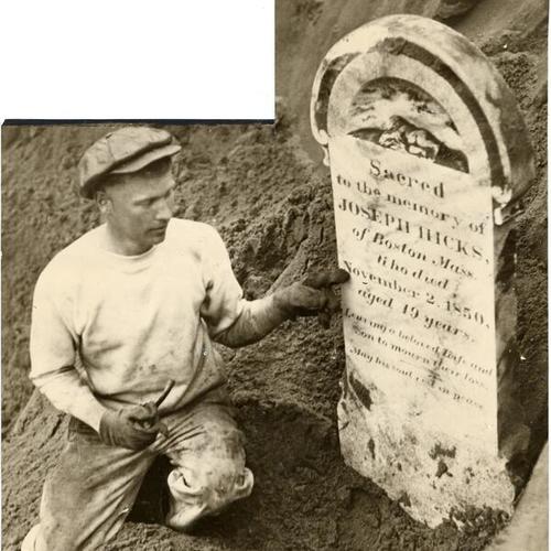 [Steam shovel operator Joseph Bush posing with gravestone uncovered during excavation for Federal Building in Civic Center]