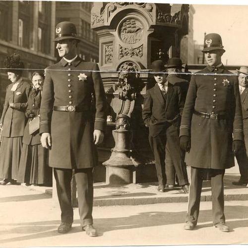[Two police officers standing in front of Lotta's Fountain on Market Street]