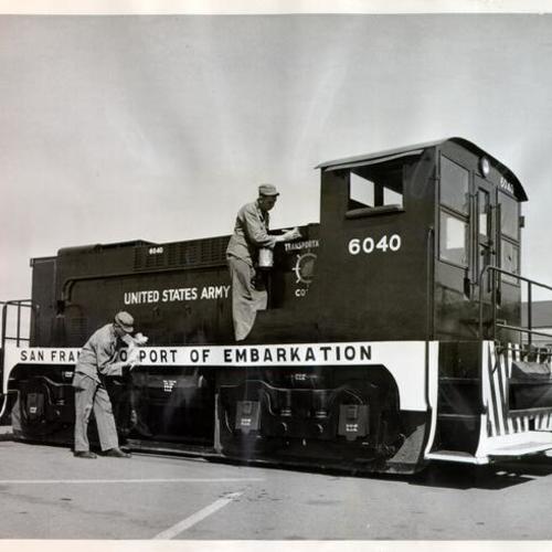 [Two Oakland Army Base soldiers touching up the Port of Embarkation's model Army Transportation Corps train]