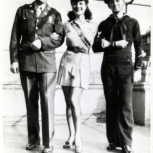 [Former burlesque queen Ann Corio models women's service uniform accompanied by private Tex Phillips and Bill Healion of the U.S. Navy]