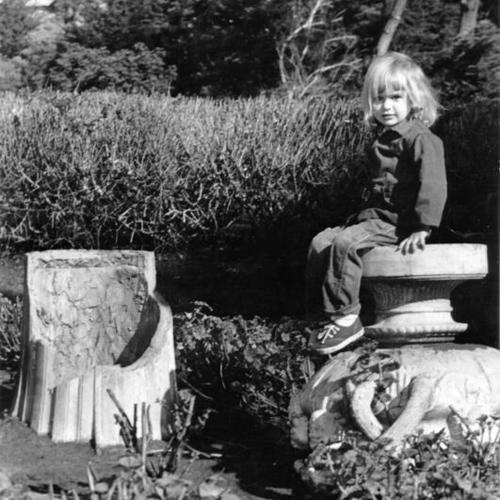 [Young girl sitting on a broken statue at Sutro Heights]