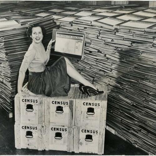 Census Bureau employee Kathleen Tate sitting on boxes and displaying portfolios
