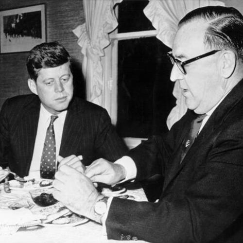 [Sen. John F. Kennedy (D-Mass), left, listens with interest to Governor Edmund G. Brown]