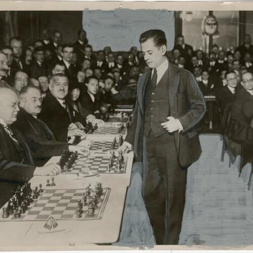 Chess champion Jose Capablanca playing a group of German experts in Berlin with audience watching