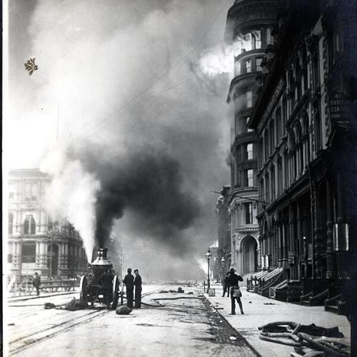 [View of fire fighters with a fire engine in front of a burning building]