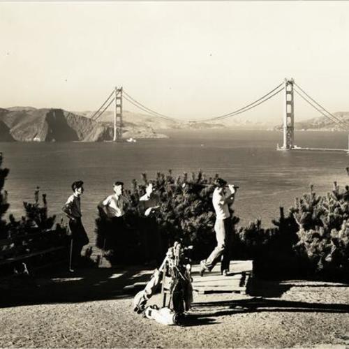 [Golfers at Lincoln Park Golf Course, with view of partially constructed Golden Gate Bridge in background]
