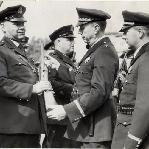 [Police Chief William Quinn with George Healy, adjusting rifle held by Richard Niebolt]