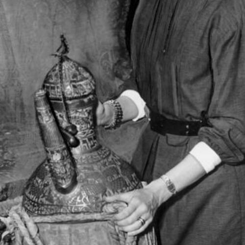 [Mrs. Stephen Townsend holding a camel water jug to be auctioned at the De Young Museum in Golden Gate Park]