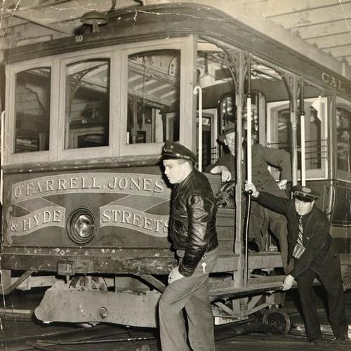 [G. W. Hunter and E. Howell rolling a cable car out of the barn at California and Hyde streets]