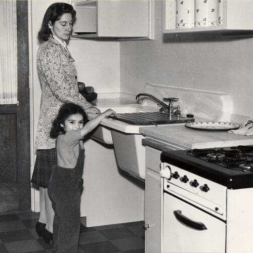 [Mrs. Alice Stinchcomb and Frances Bonnici in the kitchen of an apartment at the Sunnydale housing project]