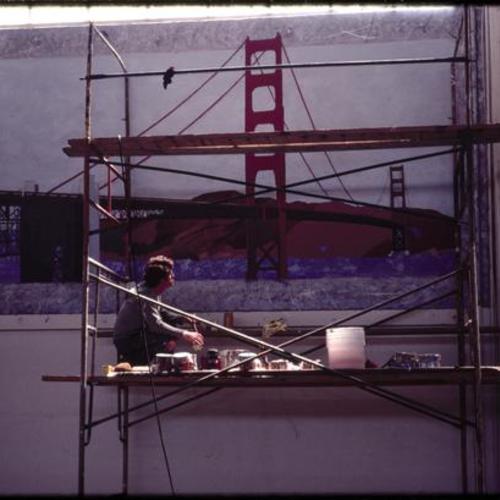 Person painting mural of Golden Gate Bridge