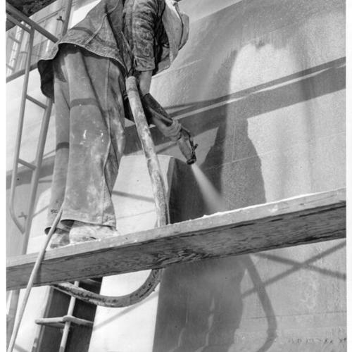 [Worker cleaning the exterior of the U. S. Mint building at Market, Buchanan and Duboce streets]