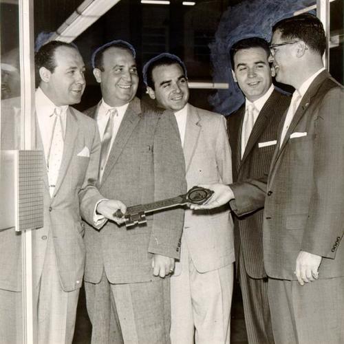 [C. Alvin Glass, president of the Mission Merchants Association, presenting a key to the "Mission Miracle Mile" to Dave, Harold, Joe and Bernie Young of Young Brothers store on Mission Street]