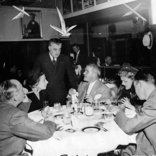 [Harry Redding, manager of the St. Domino Cafe, speaking with a group of diners]