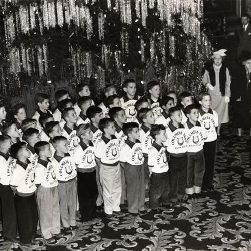 [Boys from Columbia Park Boys Club rehearsing Christmas carols in the lobby of the Fairmont Hotel under the direction of William B. Maltby]