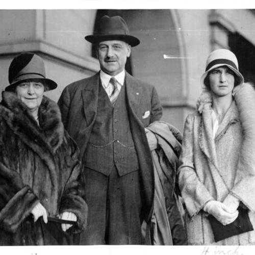 [A. P. Giannini standing in front of the Ferry Building with his wife and daughter before leaving on a trip to Europe]