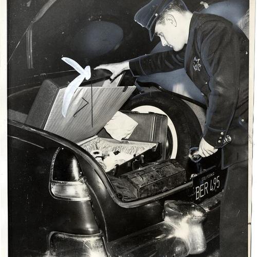 [Patrolman Dale Boyd examining the car trunk of a robbery suspect]