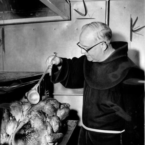[Father Alfred Boeddeker basting Thanksgiving turkeys at St. Anthony's Dining Room]
